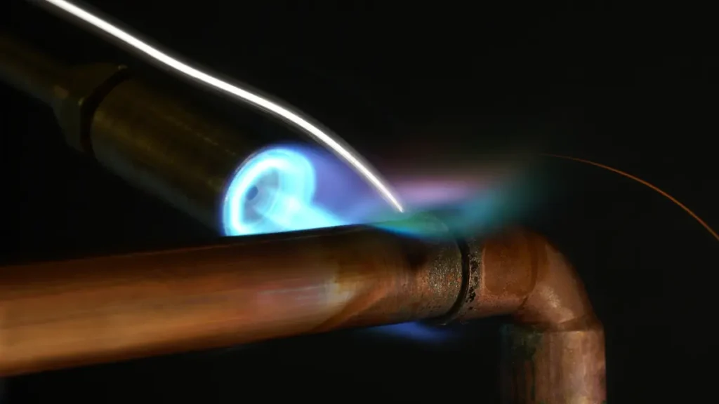 Soudure d’un tuyau en cuivre lors d’une installation ou réparation de plomberie.