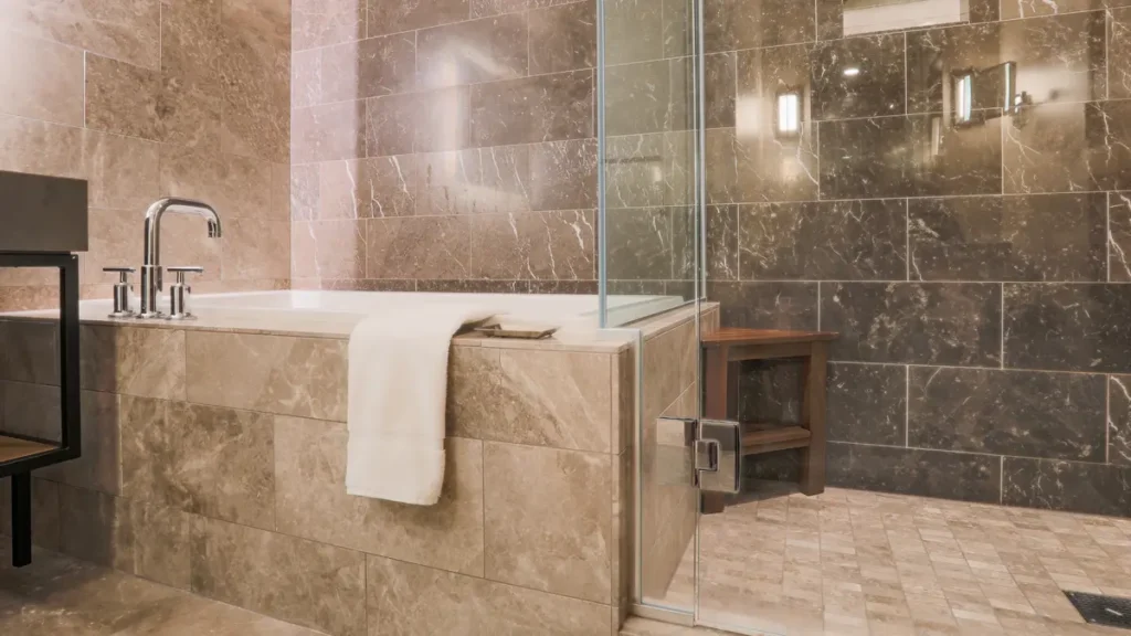 Salle de bain rénovée avec baignoire, douche vitrée et carrelage contemporain.